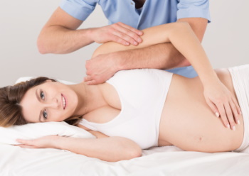 A Women is lying on the exam table , while having a prenatal adjustment - Vital Family Chiropractic - Pregnancy Chiropractic Care - Mount Pleasant, SC